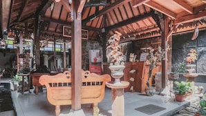 A wooden bench under a covered area with potted plants and a sign indicating affordable accommodation. - RedDoorz near Galeria Mall 2 (Yogyakarta)