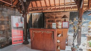 A reception area with a wooden desk, a RedDoorz sign, and a guest room sign. - RedDoorz near Galeria Mall 2 (Yogyakarta)