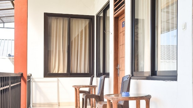 A room with a wooden door, a window with curtains, and a table with chairs. - RedDoorz near Alun Alun Wonosobo (Wonosobo)