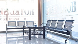 A waiting area with a bench and chairs near a window with a view of a building. - RedDoorz near Alun Alun Wonosobo (Wonosobo)