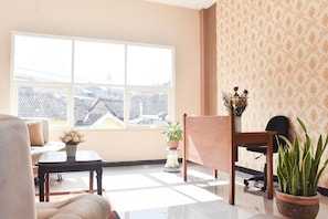 A room with a large window, a sofa, a chair, a small table, and a potted plant.