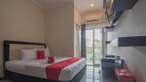A hotel room with a bed, a small table, a water bottle, and a tissue box. - RedDoorz near E Walk Mall Balikpapan (Balikpapan)