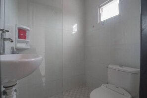 A bathroom with a white sink, a toilet, and a window. - RedDoorz near E Walk Mall Balikpapan (Balikpapan)