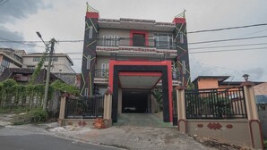 A multi-story building with a prominent entrance, a gated driveway, and a surrounding fence. - RedDoorz near E Walk Mall Balikpapan (Balikpapan)