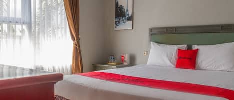 Habitación de hotel con cama, mesita de noche, ventana con cortinas y un cuadro en la pared.