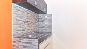 Una cocina con salpicadero de azulejos, pileta de acero inoxidable y muebles de madera.
