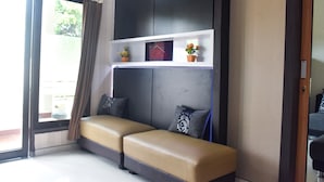 Una habitación moderna con un sofá, un pequeño estante con adornos y vistas a través de un ventanal grande.