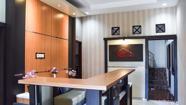 Una moderna zona de recepción con mostrador de madera, un área de estar y una escalera que lleva a un piso superior.