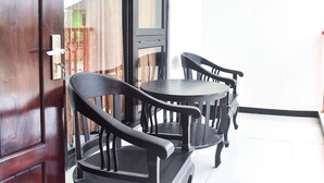 Una habitación con puerta de madera, una ventana con cortinas y una mesa redonda con dos sillas.