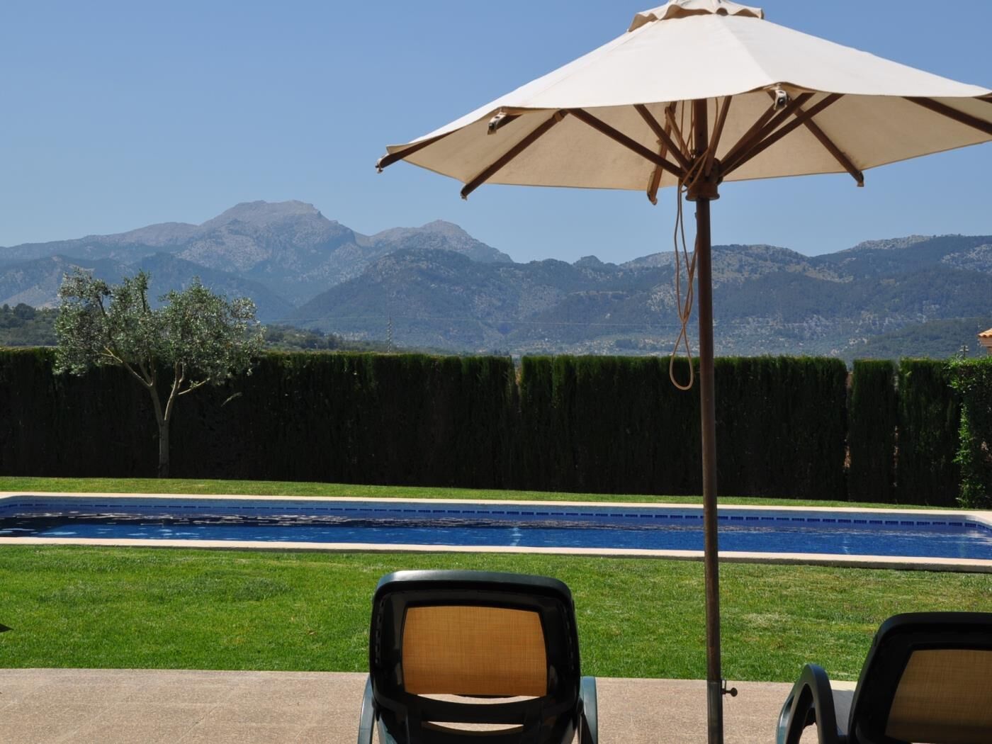 Zona de piscina amb vista a les muntanyes, una piscina i dues gandules.