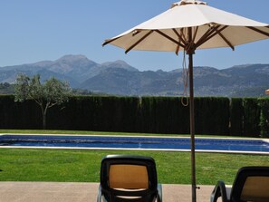 A poolside area with a view of mountains, a pool, and two lounge chairs. - Es Mussol, Finca in Sa Pobla (Sa Pobla)