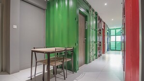 Een gang met een groene deur, een tafel met stoelen, en een rode deur.