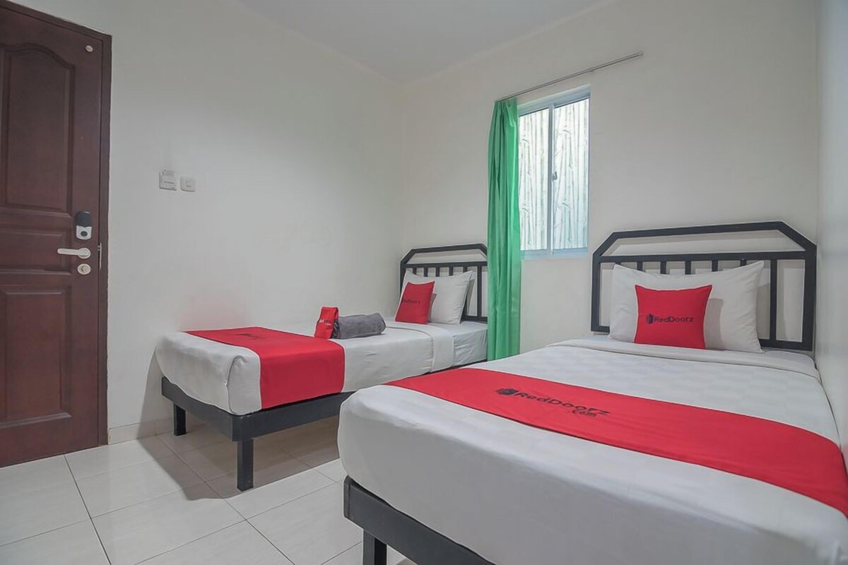 A hotel room with two beds, a door, a window with curtains, and a tiled floor.