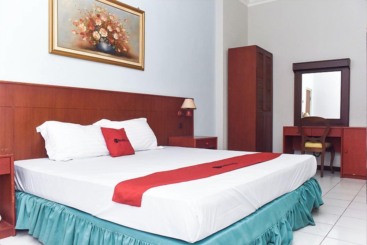 Habitación de hotel con una cama grande, un escritorio, una silla y un espejo.