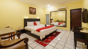 A hotel room with a bed, a desk, a chair, a mirror, and an air conditioning unit. - RedDoorz Plus near Ancol (Jakarta)