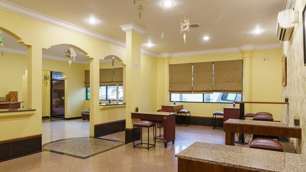 A hotel lobby with a reception desk, seating area, and large windows. - RedDoorz Plus near Ancol (Jakarta)