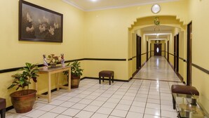 A hotel lobby with a tiled floor, a reception desk with potted plants, a bench, and a framed painting on the wall. - RedDoorz Plus near Ancol (Jakarta)