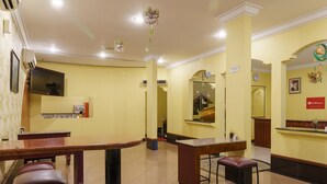 A hotel lobby with a reception desk, seating area, and a large mirror. - RedDoorz Plus near Ancol (Jakarta)