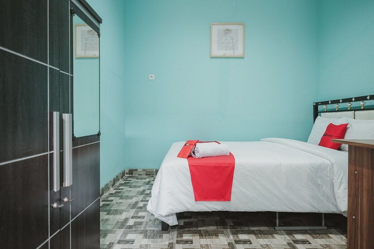 A hotel room with a bed, a wardrobe, and a tiled floor.