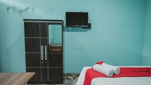 A hotel room with a bed, a wardrobe, a television, and a tiled floor. - RedDoorz near RSUD Koja (Jakarta)