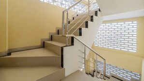 A modern staircase with metal railings and a geometric patterned wall. - RedDoorz near Plaza Atrium Senen (Jakarta)