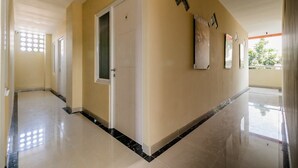 A hallway with a door marked '8', a tiled floor, and a wall with a window and artwork. - RedDoorz near Plaza Atrium Senen (Jakarta)