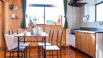 A kitchen with wooden cabinets, a dining table with chairs, a window with curtains, and a view outside.