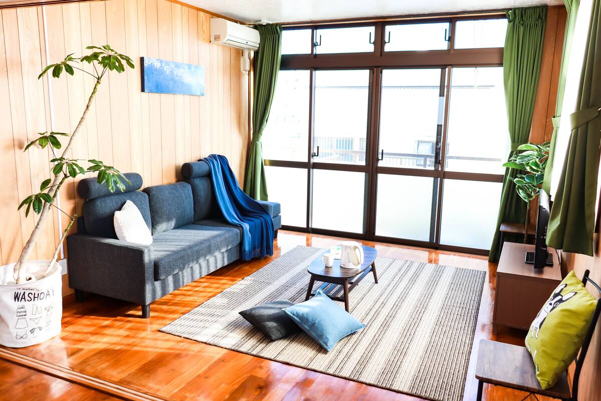 A modern living room with a sofa, coffee table, and a large window with curtains.