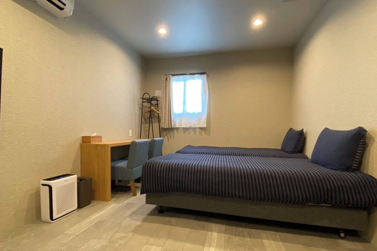A bedroom with a bed, a desk, a chair, and a window.