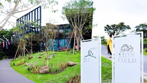 A pathway leading to a building with a modern design, featuring a sign that reads "LION FIELD" and another with a map and text. - Hotel Upi – Condominium Mihama (Chatan)