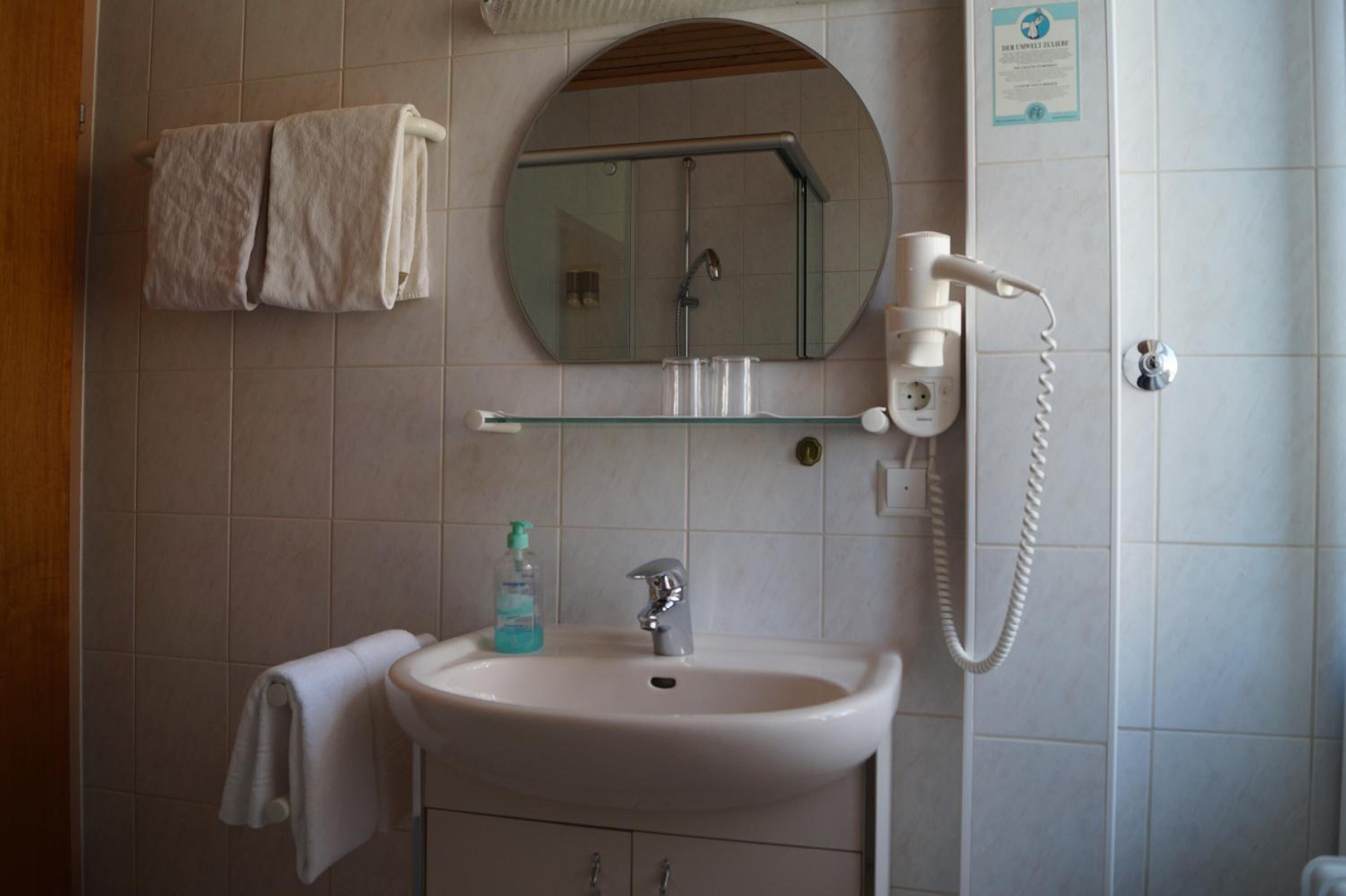 Un baño con lavamanos, espejo, toallero y secador de pelo.