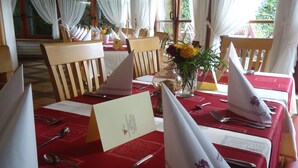 Una tavola da pranzo apparecchiata con tovaglioli bianchi, posate e una tovaglia rossa.
