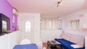En kompakt opholdsstue med spiseplads, sofa og fjernsyn.