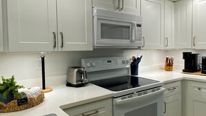 Eine moderne Küche mit weißen Schränken, einer Mikrowelle, einem Toaster und einer Kaffeemaschine.