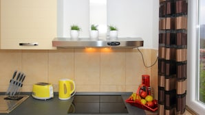 Une cuisine équipée d’un plan de travail, d’un grille-pain, d’une bouilloire, d’un bloc à couteaux et d’un panier à fruits.