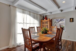 Een eetkamer met een houten tafel, stoelen en een bloemstuk.