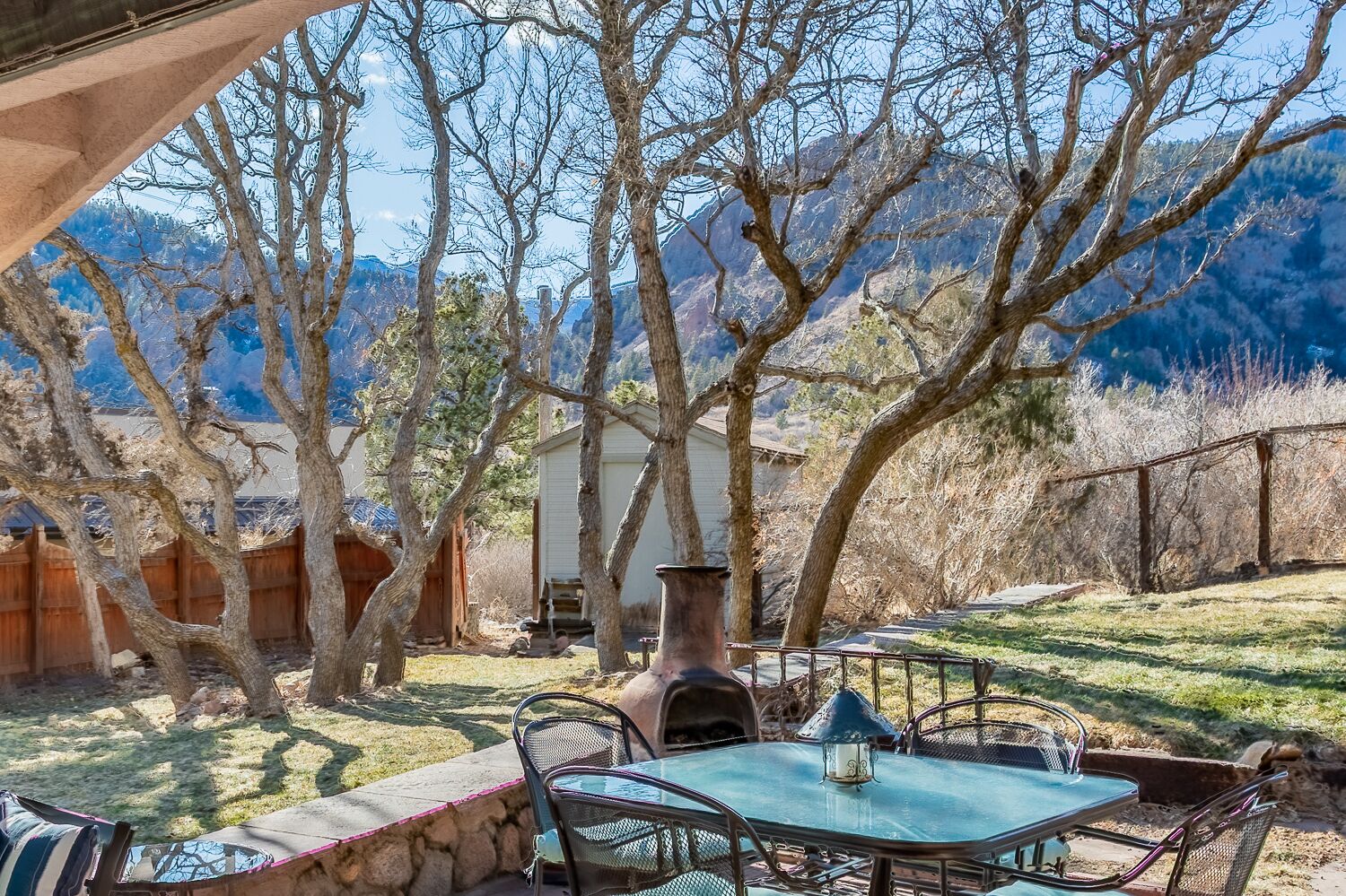 A patio with a table and chairs, surrounded by trees and a mountain view.