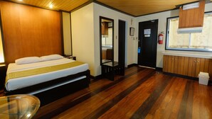 A hotel room with a bed, wooden flooring, a small kitchenette, a window with blinds, and a fire extinguisher. - Lispher Inn (Davao)