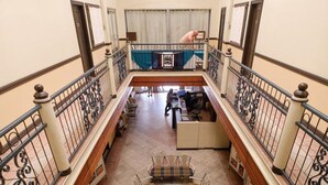 A spacious indoor area with a high ceiling, a balcony with wrought iron railings, and a seating area with tables and chairs. - Lispher Inn (Davao)