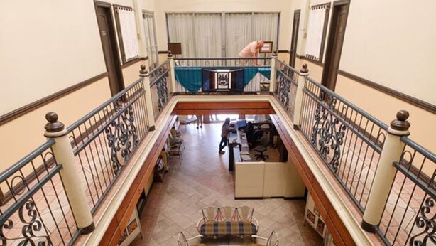 A spacious indoor area with a high ceiling, a balcony with wrought iron railings, and a seating area with tables and chairs. - Lispher Inn (Davao)