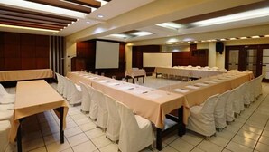 A conference room with long tables, white chairs, and a projector screen. - Lispher Inn (Davao)