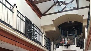 A spacious indoor area with a staircase leading to an upper level, featuring a Club of Davao sign, comfortable seating, and a decorative statue. - Lispher Inn (Davao)