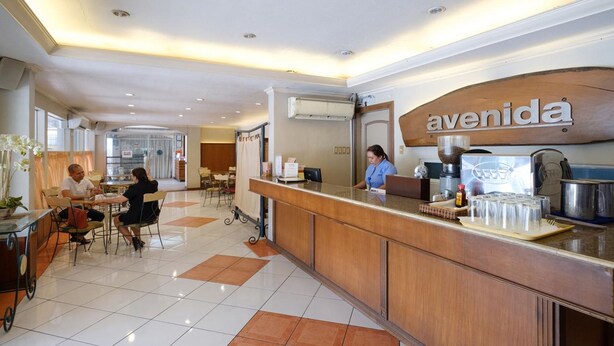 A hotel reception area with a wooden counter, a coffee machine, and a sign that reads "avenida". - Lispher Inn (Davao)