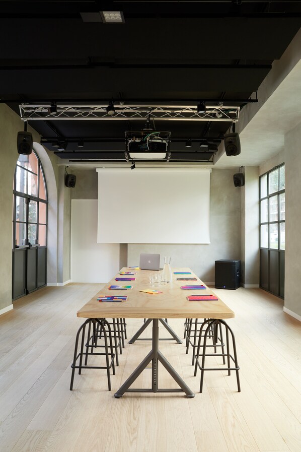 A conference room with a long table, chairs, a projector screen, and a laptop. - Combo Milano - Hostel (Milan)