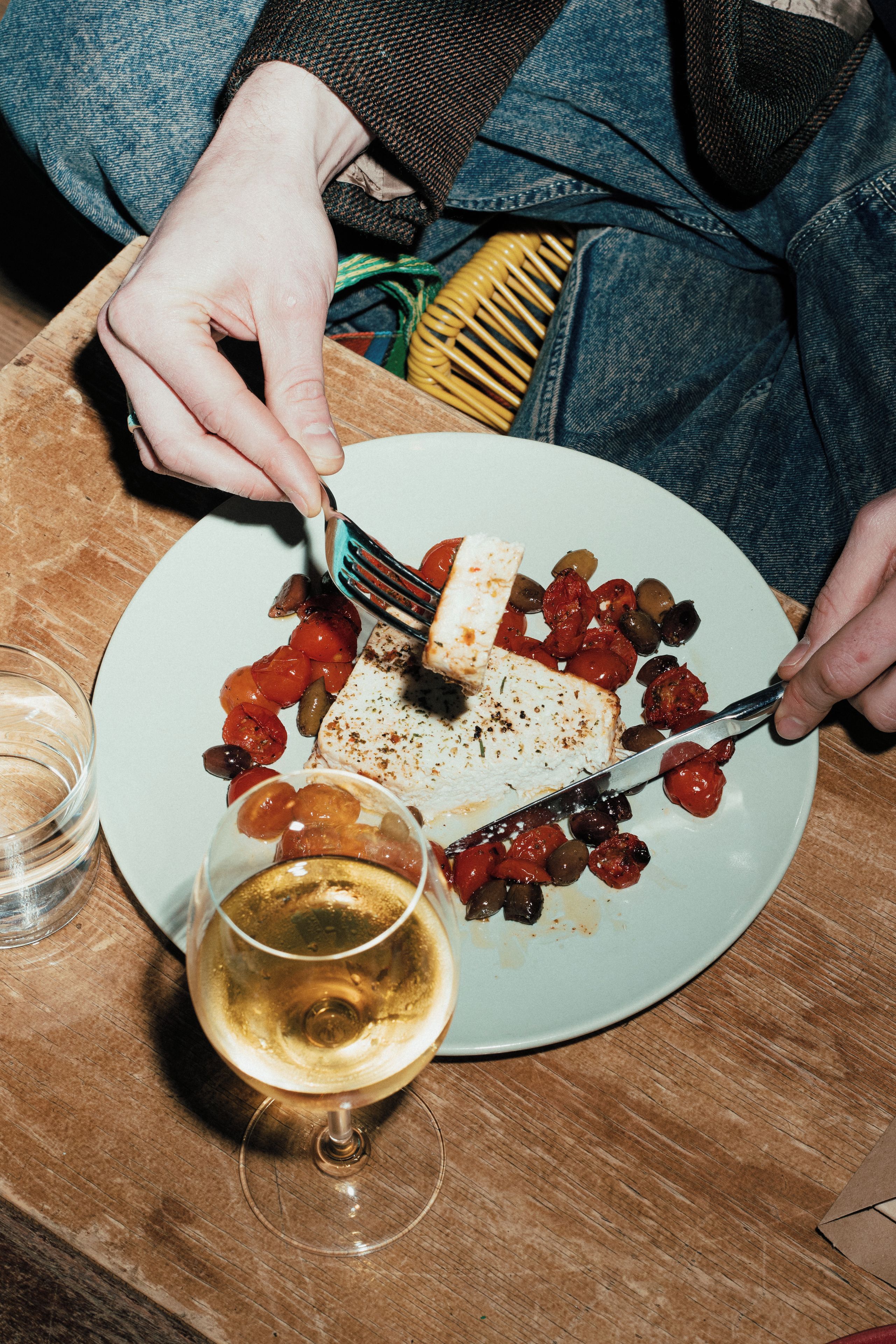 A person dining with a plate of food, a glass of wine, and a fork.