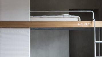 Una cama litera con una escalera, un taburete amarillo pequeño y un colchón en la cama inferior.