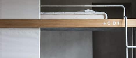 A bunk bed with a ladder, a small yellow stool, and a mattress on the lower bunk.