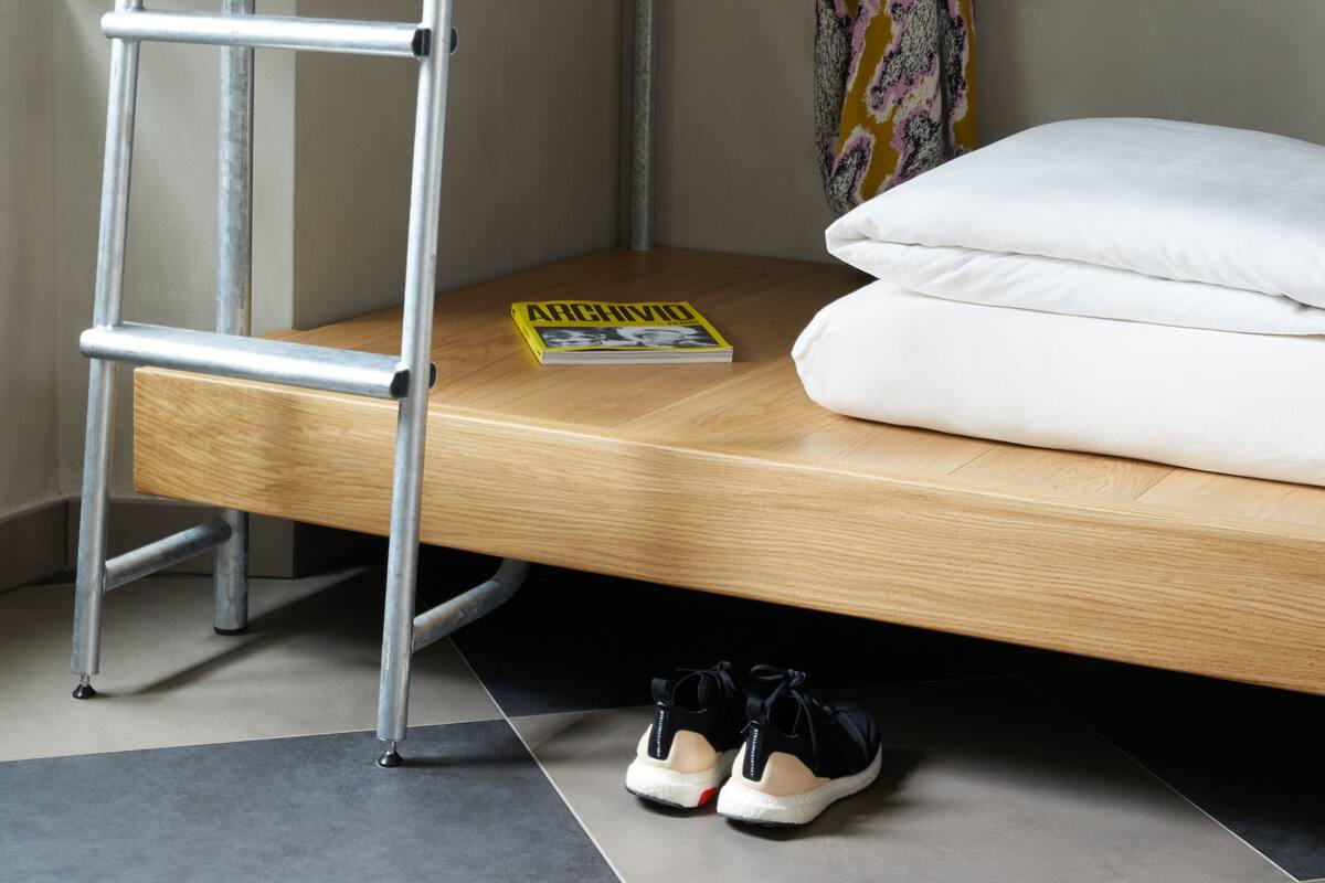 Una cama litera con escalera, una tabla de surf y un par de zapatos en el suelo.