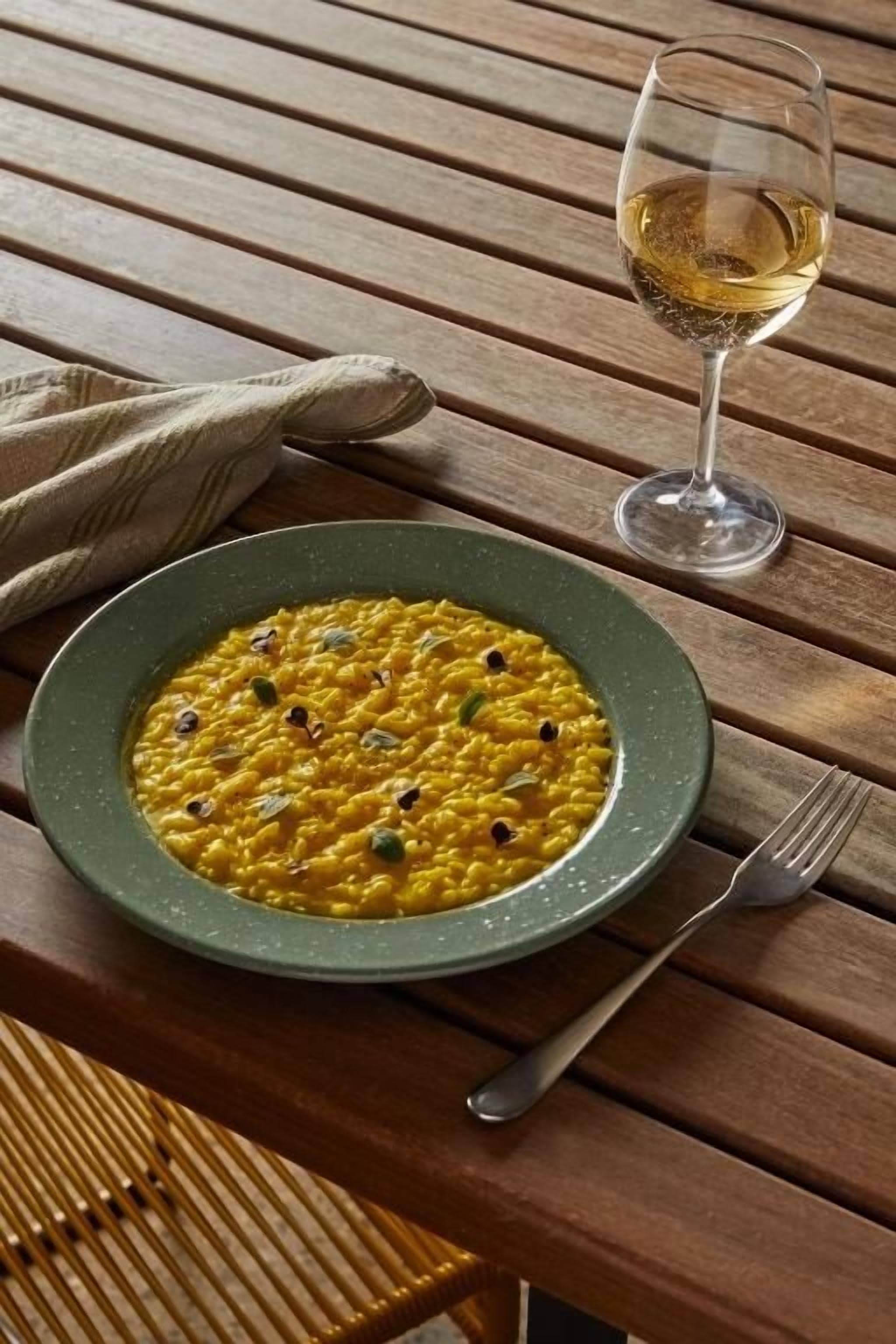 Ein Holztisch mit einem Teller Essen und einem Weinglas.