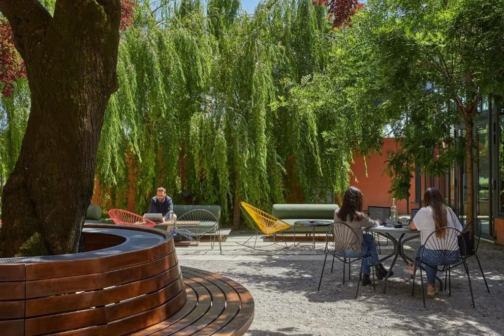 An outdoor seating area with a circular wooden bench, a table, and chairs.